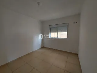 Ambiente interno de uma sala com piso de cerâmica e paredes brancas.