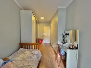 Quarto com piso de madeira e armário na área de circulação.