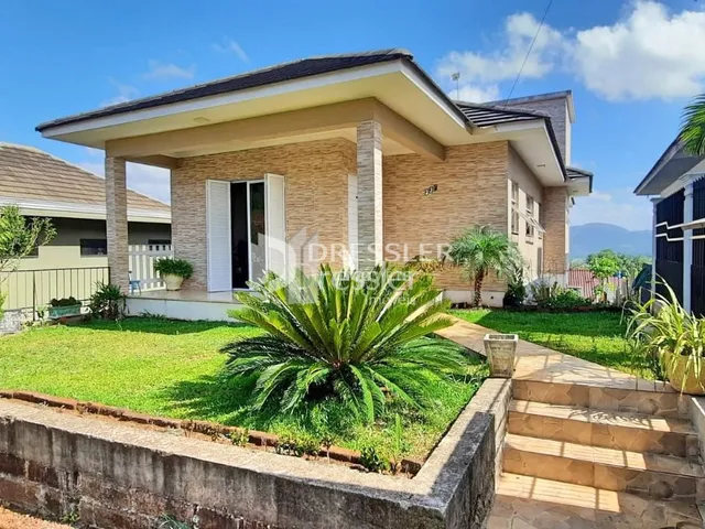 A fachada de uma casa em Lajeado, Brasil, com jardim gramado e muro de pedra.