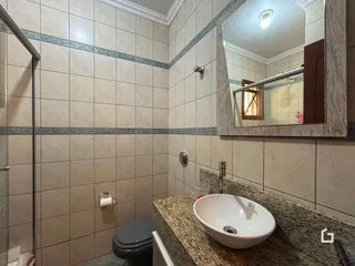 Interior de um banheiro com revestimento cerâmico e bancada de granito.