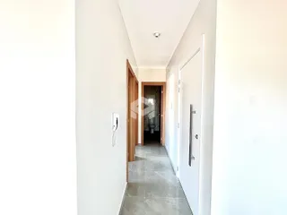 Corredor interno de uma residência com paredes brancas e piso claro.