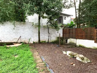 Vista externa de uma propriedade com muro de tijolos e jardim.