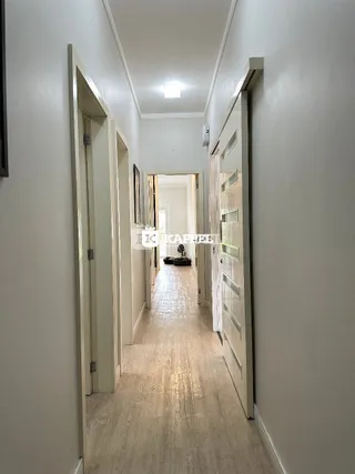 Corredor interno de um imóvel com paredes brancas e piso claro.