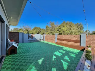Área externa pavimentada com piso verde em um quintal.