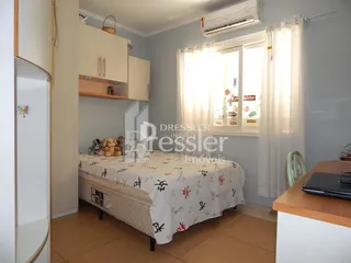 Quarto com cama e armário branco em ambiente interno.