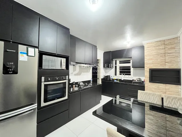 Foto de uma cozinha moderna com armários pretos e eletrodomésticos de aço inoxidável.