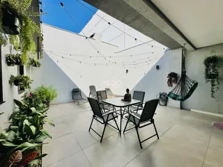 Área externa ampla com piso claro e mobiliário de jantar.