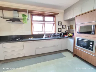 Foto de uma cozinha moderna com armários brancos e bancada escura.