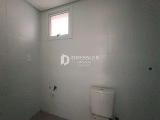 Foto interna de um cômodo com parede branca e janela.