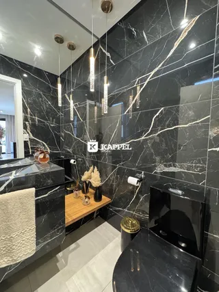 Banheiro com revestimento em mármore preto e iluminação moderna.