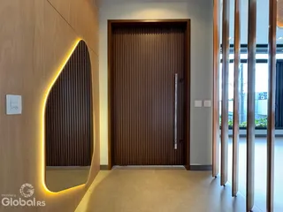 Hall de entrada com revestimento de madeira e porta de madeira escura.