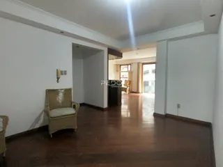 A sala de estar apresenta piso de madeira polida e paredes brancas.