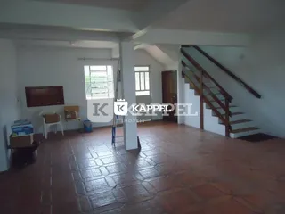 Ambiente interno com piso de ladrilho e escadaria de madeira.