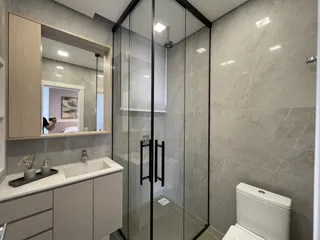 Banheiro moderno com revestimento em tons de cinza e vidro.