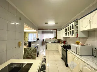 Interior de uma cozinha com armários brancos e piso de cerâmica.
