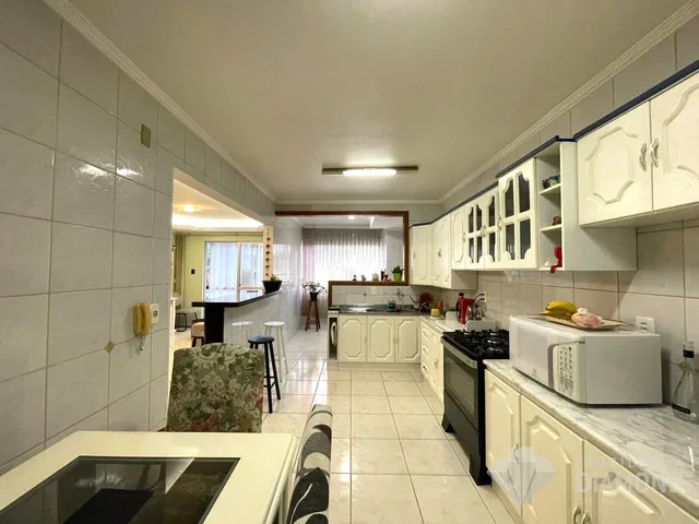 Interior de uma cozinha com armários brancos e piso de cerâmica.