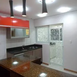Foto interna de uma cozinha com armários e bancadas.