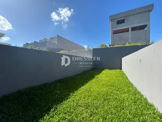 Vista externa de um terreno com gramado verde e muros altos.