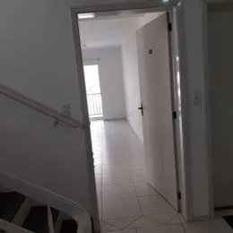 Corredor interno com paredes brancas e piso claro.