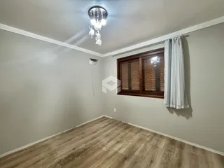 Ambiente interno de uma sala com piso de madeira clara e moldura de teto.