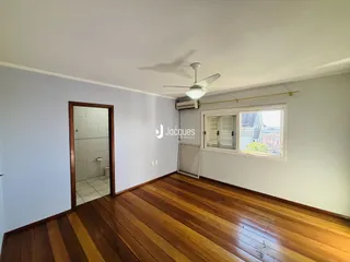 Ambiente interno com piso de madeira e porta de acesso a um banheiro.
