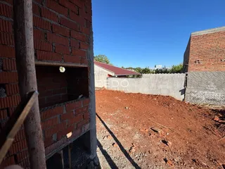 Vista externa de paredes de tijolo e terra de um terreno.
