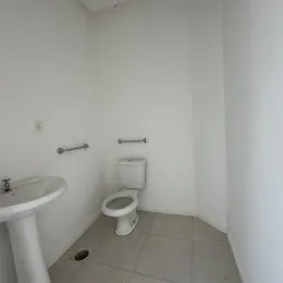 Foto interna de um banheiro com vaso sanitário branco e paredes brancas.