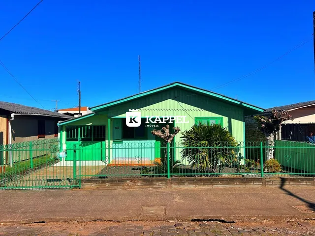 Fachada de uma residência verde em Lajeado, Brasil, com cerca frontal.