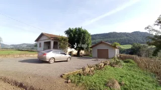 Vista externa de uma propriedade rural com duas construções e paisagem montanhosa ao fundo.