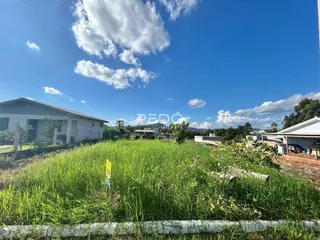 Vista externa de uma propriedade com grama alta sob um céu azul.