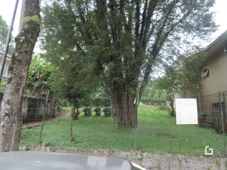 Vista externa de um terreno com vegetação e cerca.