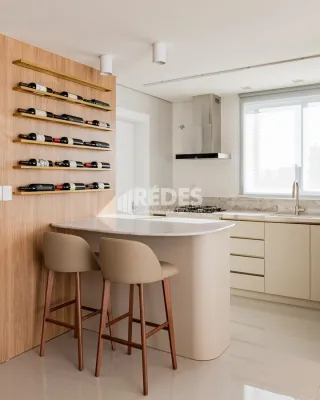 Vista de uma cozinha moderna com ilha central e bancada clara.