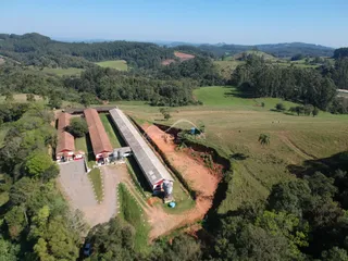 Vista aérea de uma propriedade rural em Lajeado, Brasil, cercada por vegetação e campos.