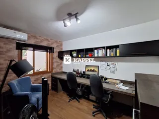Foto de um escritório com mesa de madeira e estantes em um ambiente interno.
