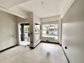 Hall de entrada com piso de cerâmica clara e paredes brancas.