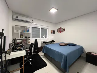 Quarto com cama e espaço de trabalho em ambiente claro.