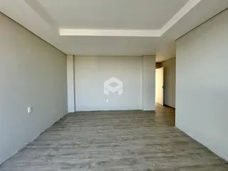 Ambiente interno de uma sala ampla com piso de madeira clara.
