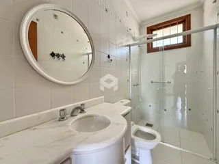 Banheiro com revestimento branco e box de vidro.