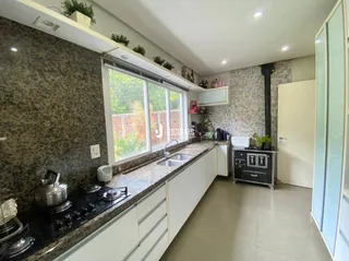 Vista interna de uma cozinha com armários brancos e bancada de granito.