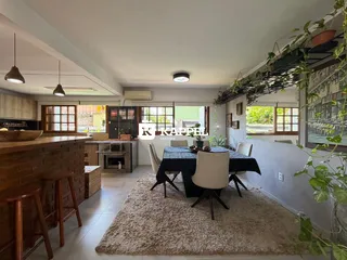 Sala de jantar com mesa escura e bancada de madeira no ambiente.