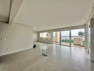 Ambiente interno amplo com piso de concreto e portas de vidro que dão para o exterior.