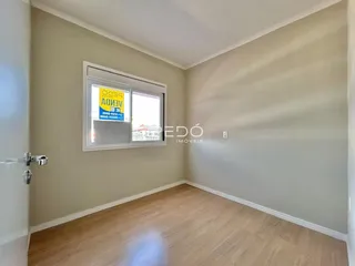 Ambiente interno de uma sala com piso de madeira clara e paredes neutras.