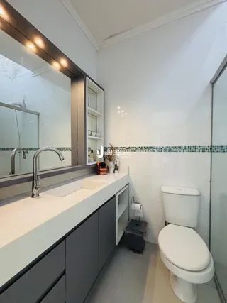 Banheiro moderno com bancada e vaso sanitário em Lajeado.