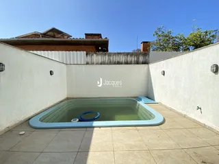 Piscina externa em um pátio branco.