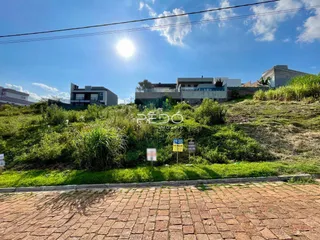 Vista externa de uma propriedade com terreno gramado e edificações ao fundo.