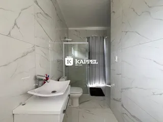 Banheiro com revestimento em mármore branco e bancada branca.