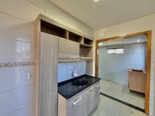 Cozinha com armários de madeira e bancada escura em um imóvel no Brasil.
