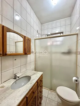 Foto de um banheiro com bancada e box de vidro.