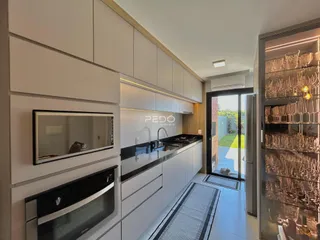 Cozinha moderna com armários brancos e bancadas escuras.