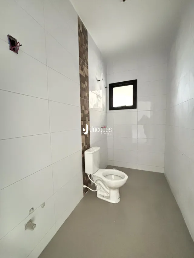 Foto de um banheiro interno com revestimento de cerâmica branca.